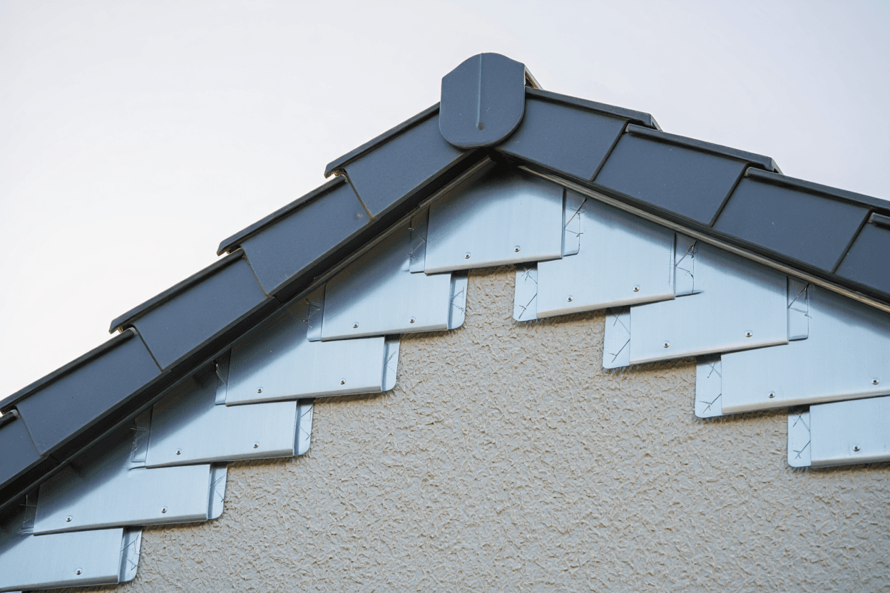 Professional roofer installing step flashing where roof meets exterior wall